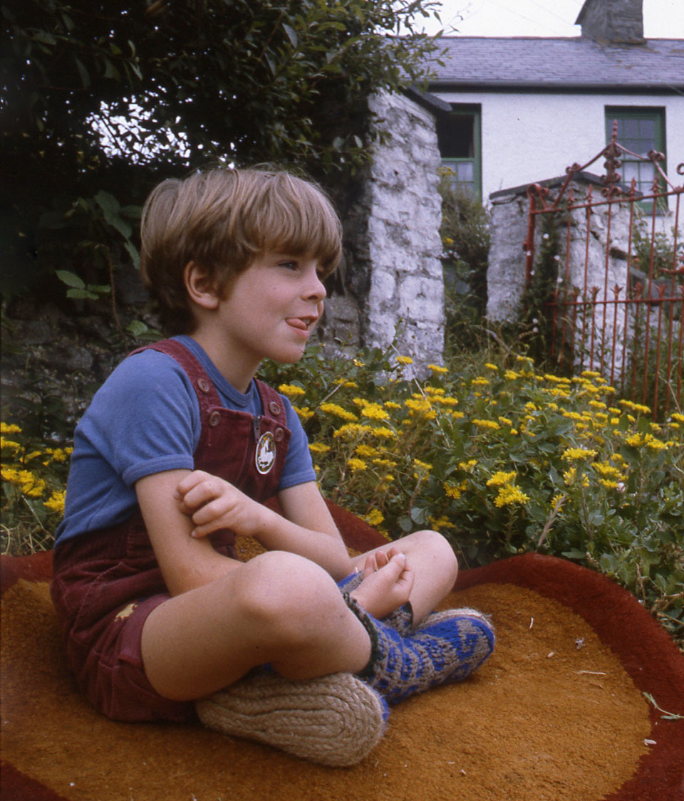 Archie-sitting-on-a-handmade-round-rug-in-my-rock-garden-wearing-his-blue-Afgan-socks-Rope-Soles-that-I-plaited-and-sewed-on..jpg